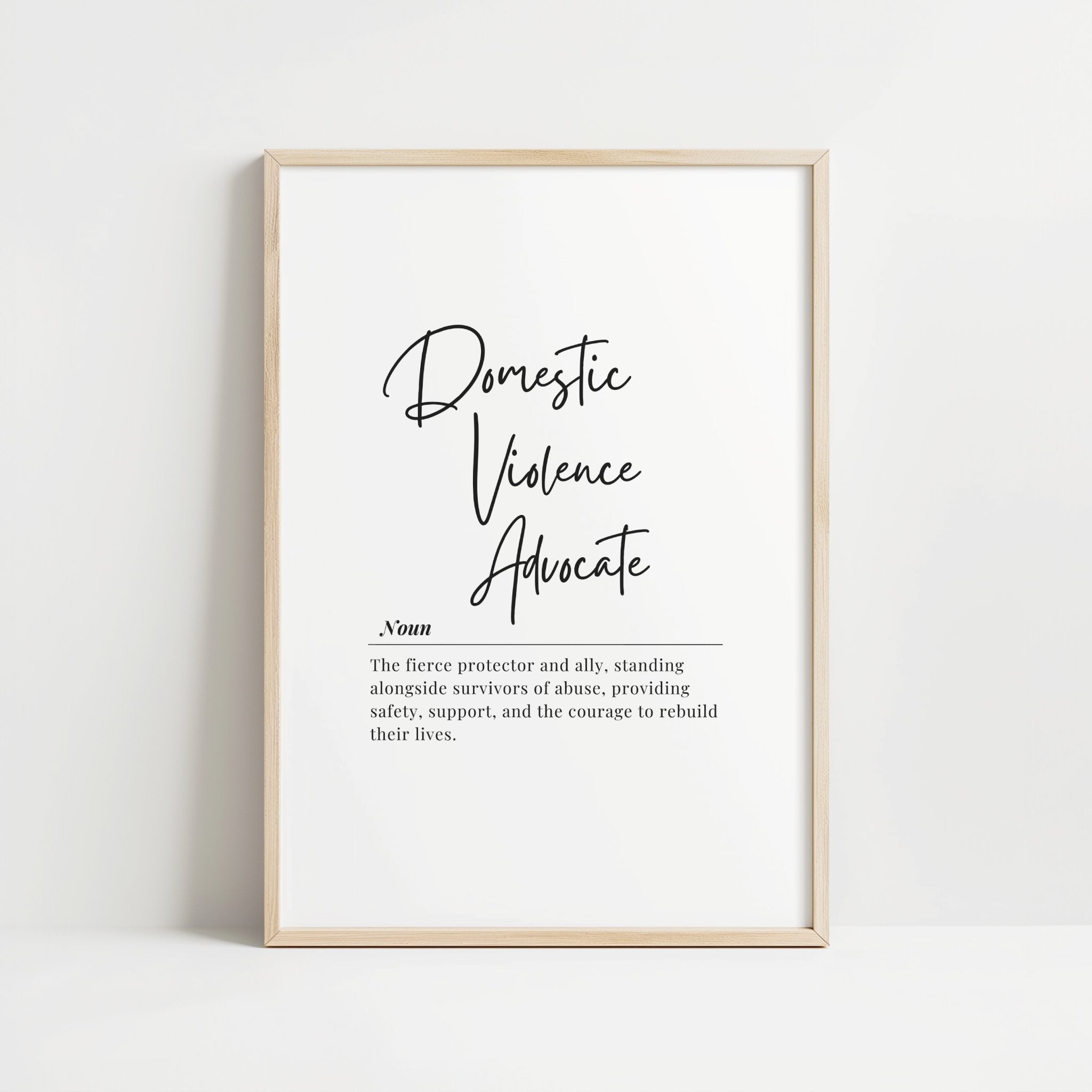Elegant black and white typography print featuring 'Domestic Violence Advocate' in bold script with supportive definition in serif font against clean white background, framed in natural wood.