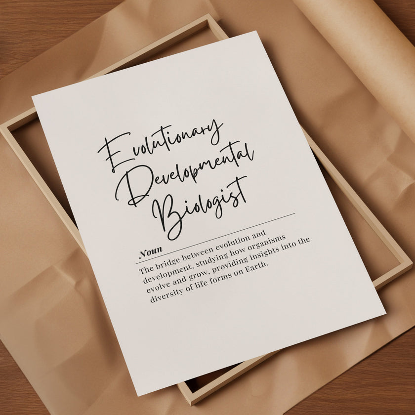 Elegant black typography print featuring 'Evolutionary Developmental Biologist' in modern script against white background with definition text in clean serif font, framed in natural wood