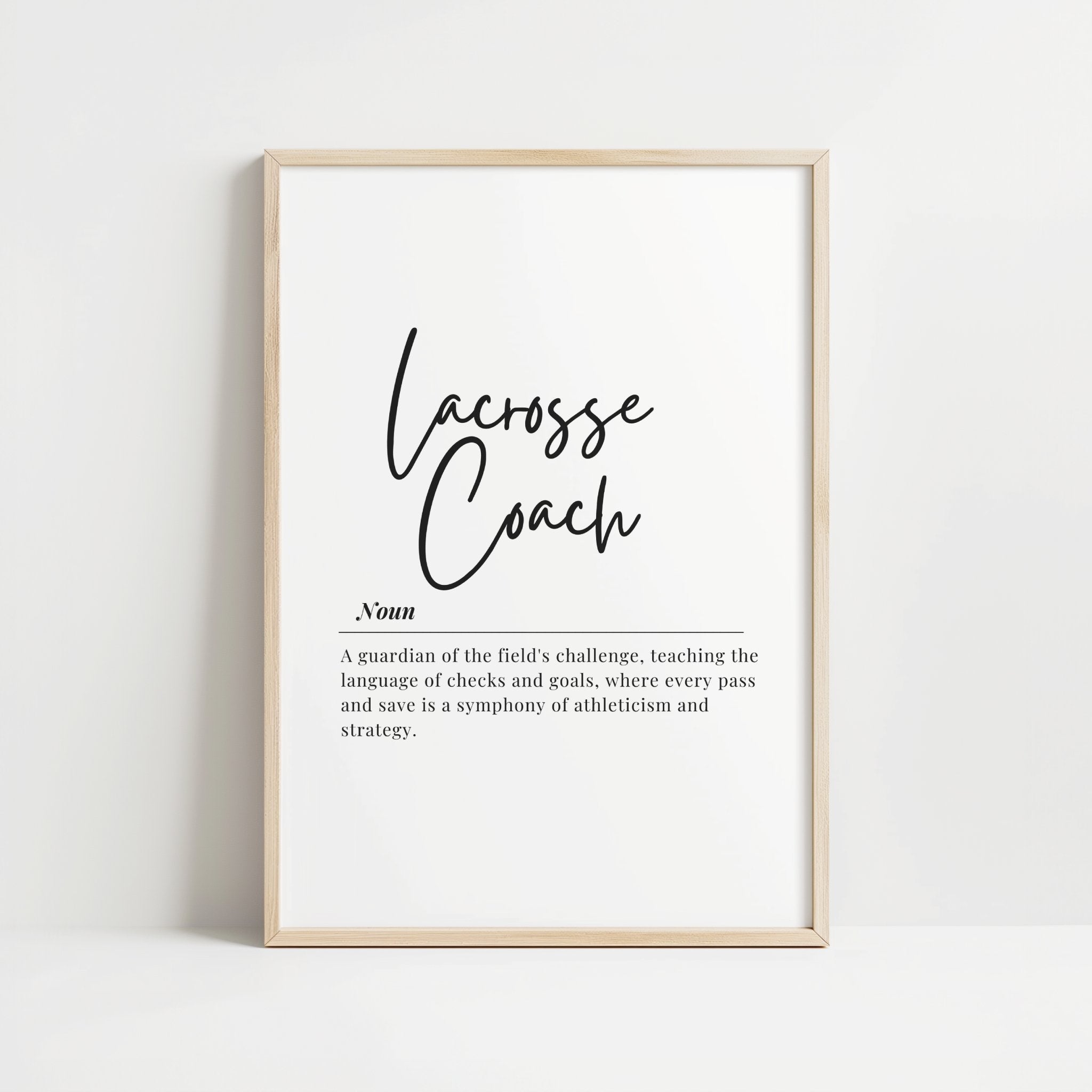 Minimalist black script typography displaying 'Lacrosse Coach' definition against white background, framed in natural wood, perfect for athletic environments and modern office spaces.