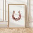 Minimalist copper horseshoe against white background in rustic frame, conveying warmth and protection through simple, elegant design perfect for farmhouse or Scandinavian decor.