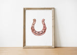 Minimalist copper horseshoe against white background in rustic frame, conveying warmth and protection through simple, elegant design perfect for farmhouse or Scandinavian decor.