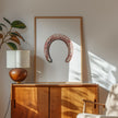 Minimalist vintage horseshoe print in warm copper tones against crisp white background, featuring rustic texturing and simple composition perfect for farmhouse and Scandinavian decor