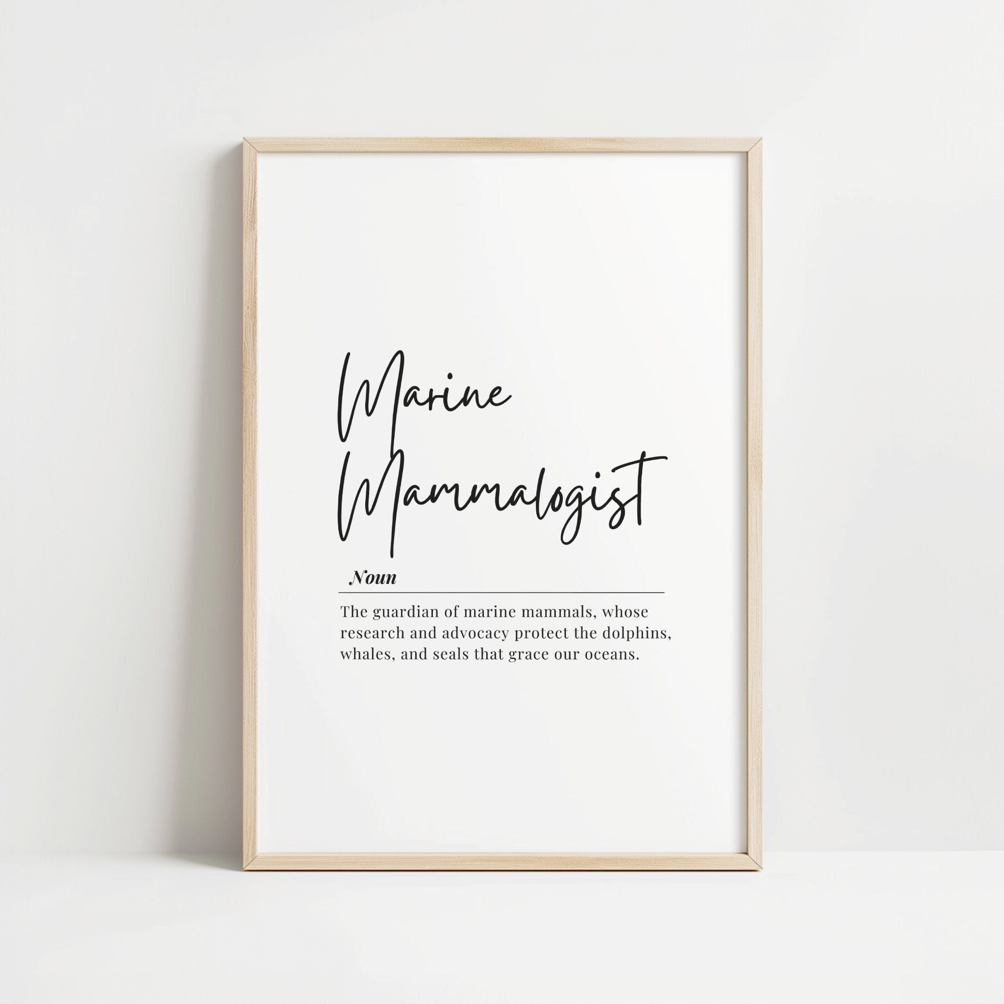 Minimalist typography print featuring 'Marine Mammalogist' in elegant black script with serif definition text against white background, framed in oak, celebrating ocean conservation professionals.