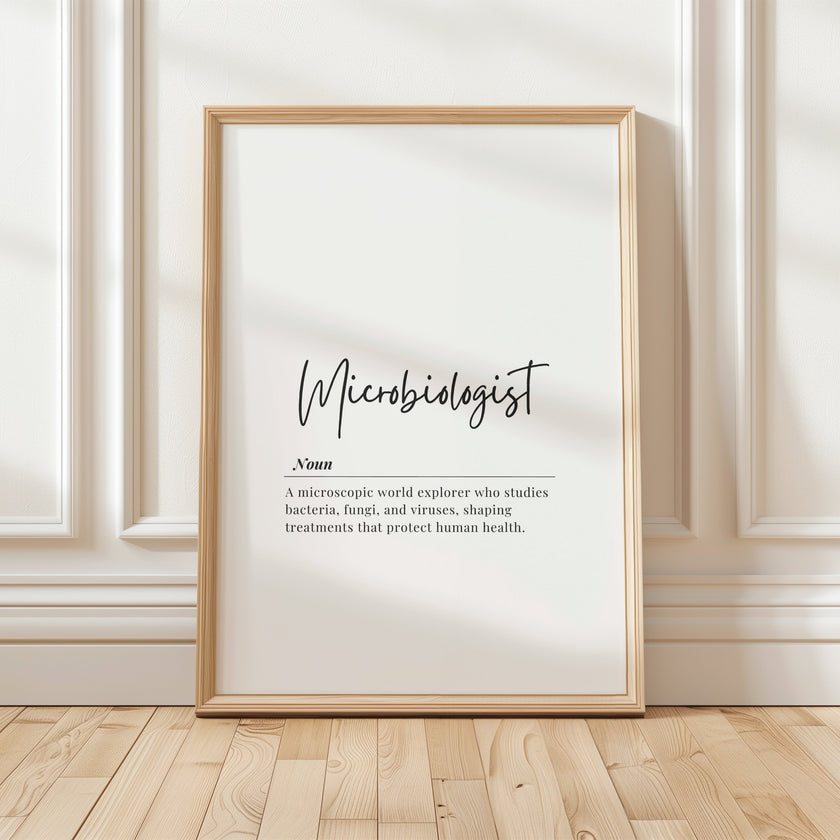 Minimalist typography print featuring 'Microbiologist' in bold cursive against white background with professional black serif definition text below, creating a clean intellectual aesthetic in a simple wooden frame.