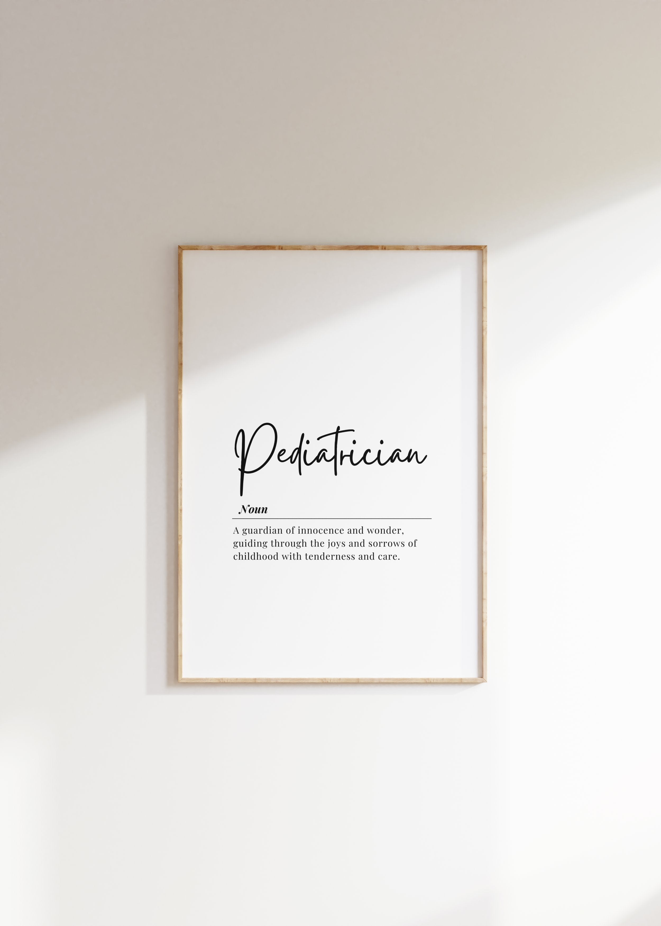 Minimalist black typography on white background displaying 'Pediatrician' definition with elegant script, framed in clean wood, perfect for pediatric offices and waiting rooms.