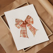 Vintage plaid bow in warm terracotta and cream tones against a white background, featuring intricate pattern detail with rustic charm perfect for farmhouse-inspired spaces.