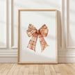 Vintage plaid bow in warm terracotta and cream tones against a white background, featuring intricate pattern detail with rustic charm perfect for farmhouse-inspired spaces.
