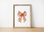 Vintage plaid bow in warm terracotta and cream tones against a white background, featuring intricate pattern detail with rustic charm perfect for farmhouse-inspired spaces.