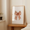 Vintage plaid bow in warm terracotta and cream tones against a white background, featuring intricate pattern detail with rustic charm perfect for farmhouse-inspired spaces.