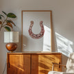 Elegant minimalist horseshoe in muted rose gold against white background, featuring detailed rivets and rustic finish, framed in natural wood for good luck charm in modern farmhouse decor.