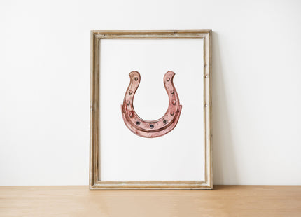Elegant minimalist horseshoe in muted rose gold against white background, featuring detailed rivets and rustic finish, framed in natural wood for good luck charm in modern farmhouse decor.