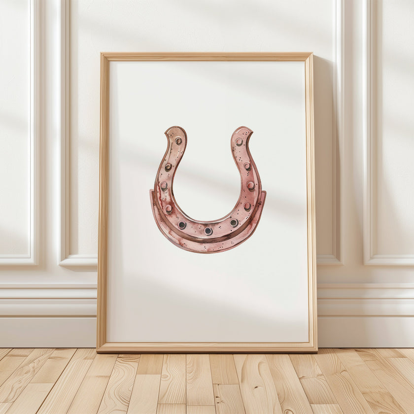 Elegant minimalist horseshoe in muted rose gold against white background, featuring detailed rivets and rustic finish, framed in natural wood for good luck charm in modern farmhouse decor.