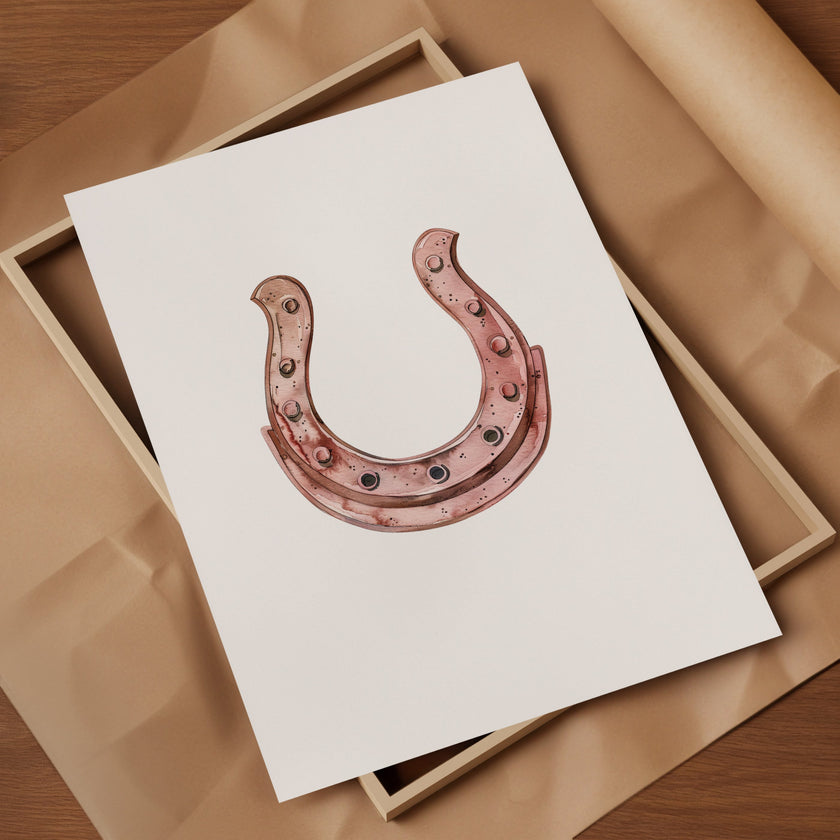 Elegant minimalist horseshoe in muted rose gold against white background, featuring detailed rivets and rustic finish, framed in natural wood for good luck charm in modern farmhouse decor.