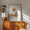 Minimalist watercolor print featuring silhouettes of a person and dog against a vivid burnt orange sunset in a desert landscape, conveying serenity and adventure in warm earthy tones.