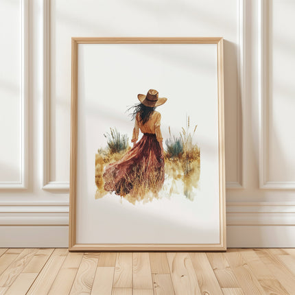 Solitary figure in flowing dress and wide-brimmed hat stands in desert landscape with burnt sienna, mustard and tan tones creating a serene, peaceful atmosphere against white background.