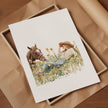 Serene watercolor scene of woman and horse in meadow, depicted in warm chestnut brown, sage green and gold tones on minimalist white background with rustic wooden frame elements