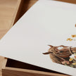 Serene watercolor scene of woman and horse in meadow, depicted in warm chestnut brown, sage green and gold tones on minimalist white background with rustic wooden frame elements