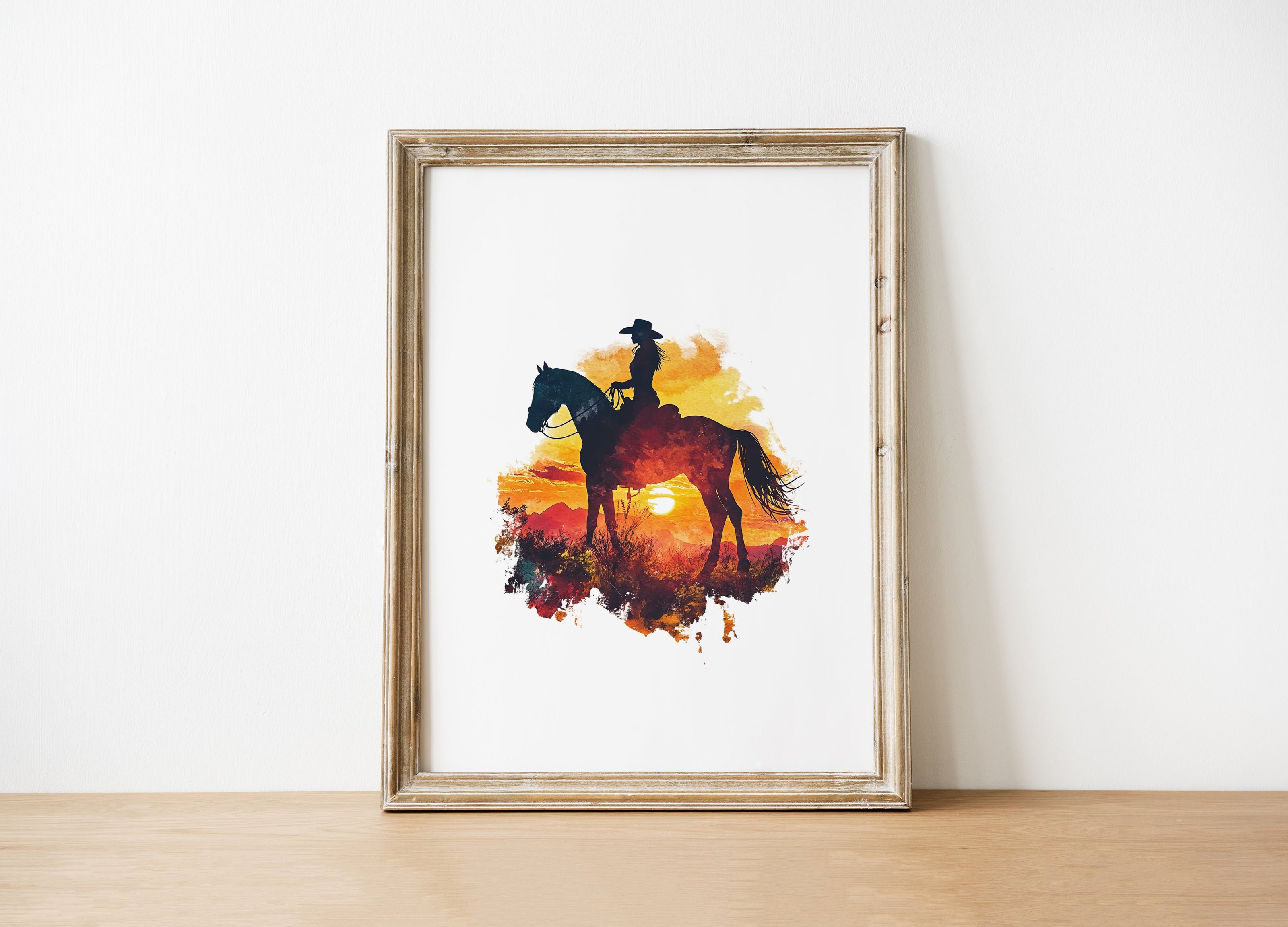 Dramatic silhouette of cowboy on horseback against vibrant orange, red and yellow sunset, featuring textured watercolor splashes creating a nostalgic, adventurous western landscape perfect for rustic decor.