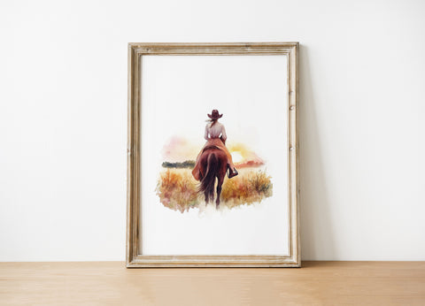 Watercolor silhouette of cowgirl riding horse at sunset with warm earth tones of sienna, pink and gold against white background, creating serene rustic ambiance perfect for farmhouse decor.