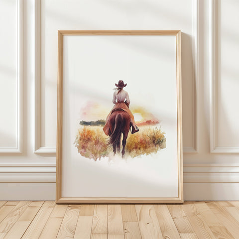Watercolor silhouette of cowgirl riding horse at sunset with warm earth tones of sienna, pink and gold against white background, creating serene rustic ambiance perfect for farmhouse decor.