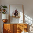 Watercolor cowgirl riding horse at sunset with soft pastel tones of blush pink, amber and lavender, creating a serene western-themed focal point against white space.