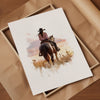 Watercolor cowgirl riding horse at sunset with soft pastel tones of blush pink, amber and lavender, creating a serene western-themed focal point against white space.