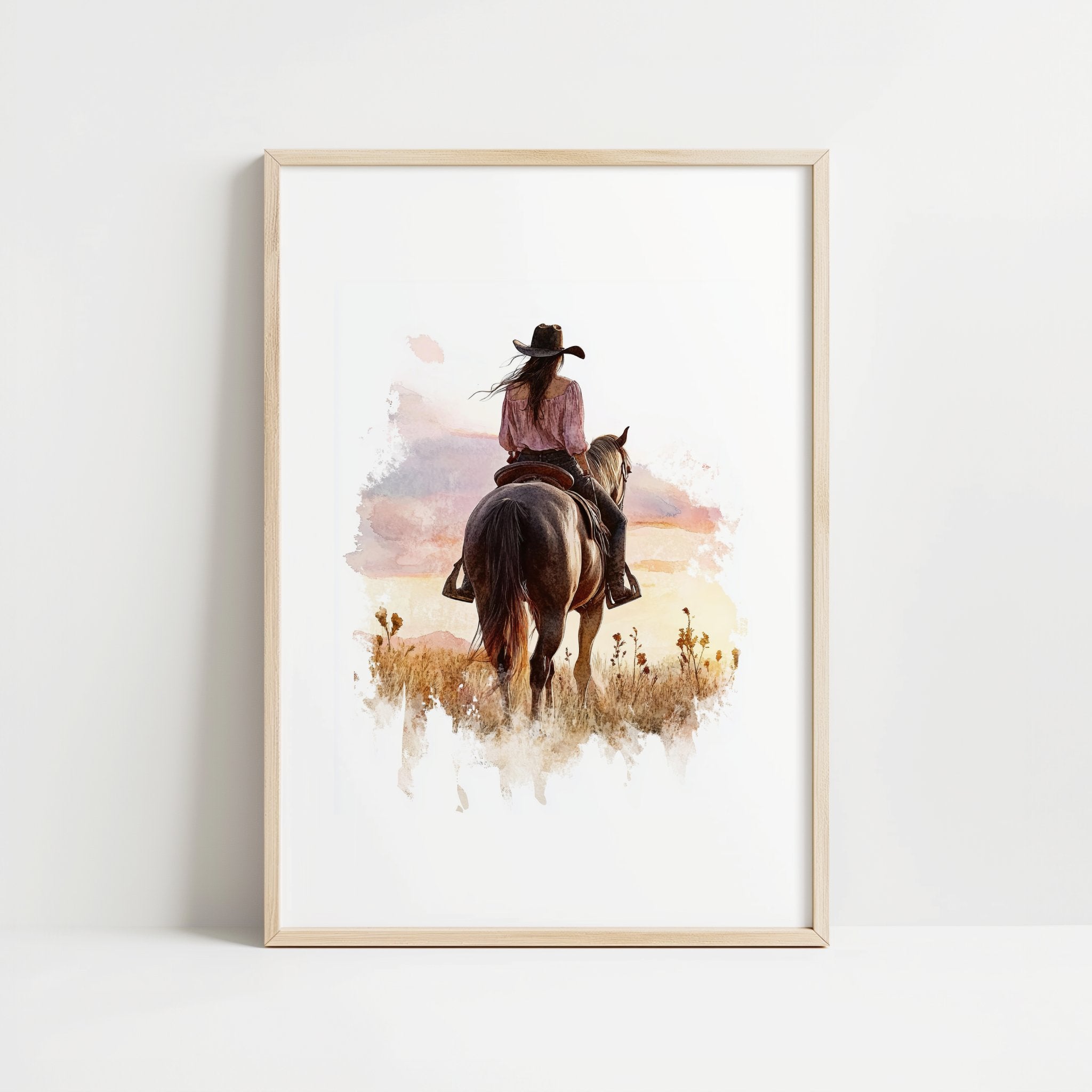 Watercolor cowgirl riding horse at sunset with soft pastel tones of blush pink, amber and lavender, creating a serene western-themed focal point against white space.