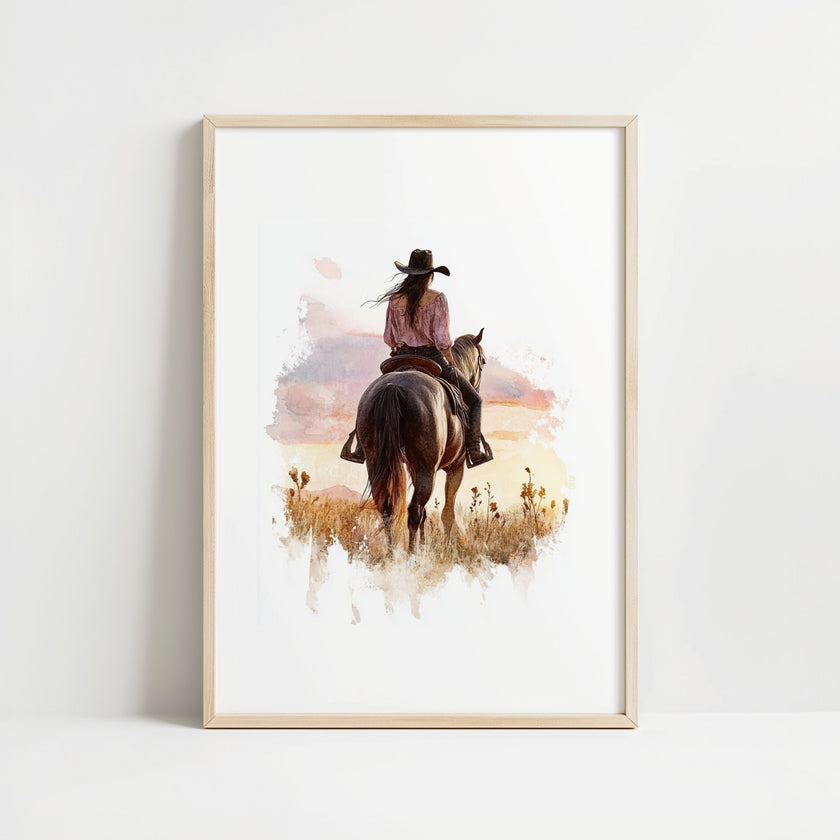 Watercolor cowgirl riding horse at sunset with soft pastel tones of blush pink, amber and lavender, creating a serene western-themed focal point against white space.