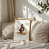 Watercolor cowgirl riding horse at sunset with soft pastel tones of blush pink, amber and lavender, creating a serene western-themed focal point against white space.