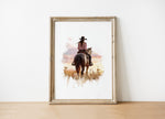 Watercolor cowgirl riding horse at sunset with soft pastel tones of blush pink, amber and lavender, creating a serene western-themed focal point against white space.
