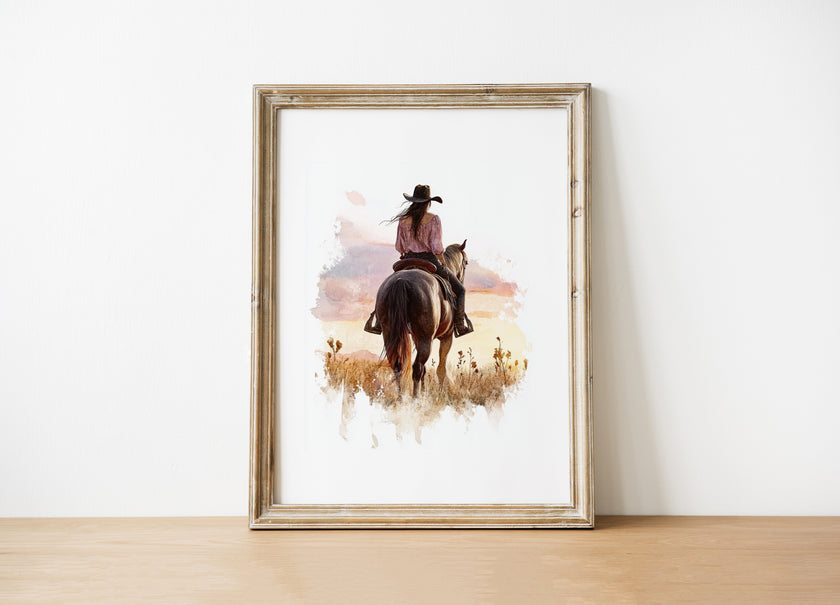 Watercolor cowgirl riding horse at sunset with soft pastel tones of blush pink, amber and lavender, creating a serene western-themed focal point against white space.
